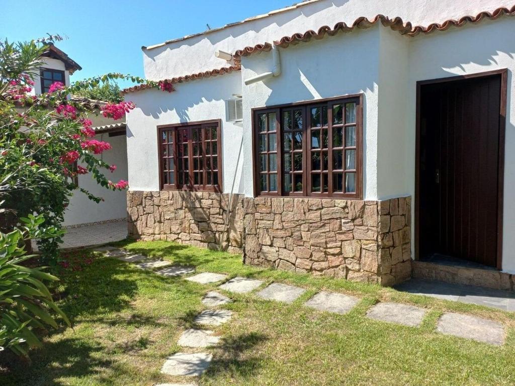 una casa bianca con una porta e un muro di pietra di Suíte 1 no centro de Búzios a Búzios