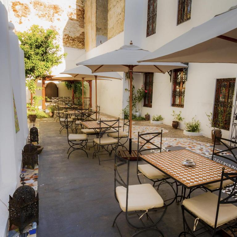 a courtyard with tables and chairs and umbrellas at Hotel Blanco Riad in Tetouan