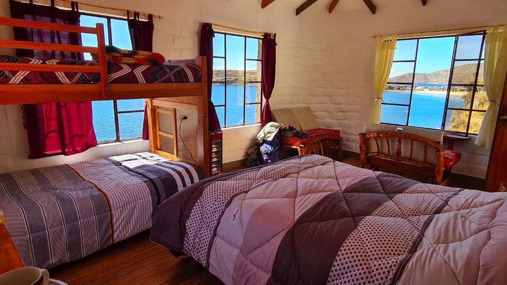 a bedroom with two beds and a view of the ocean at ECO CABAÑA INTIWAT'A in Comunidad Challapampa