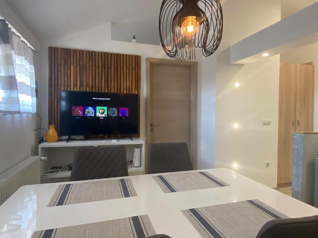 a dining room with a white table and a television at Albert apartments Zagreb airport in Velika Gorica