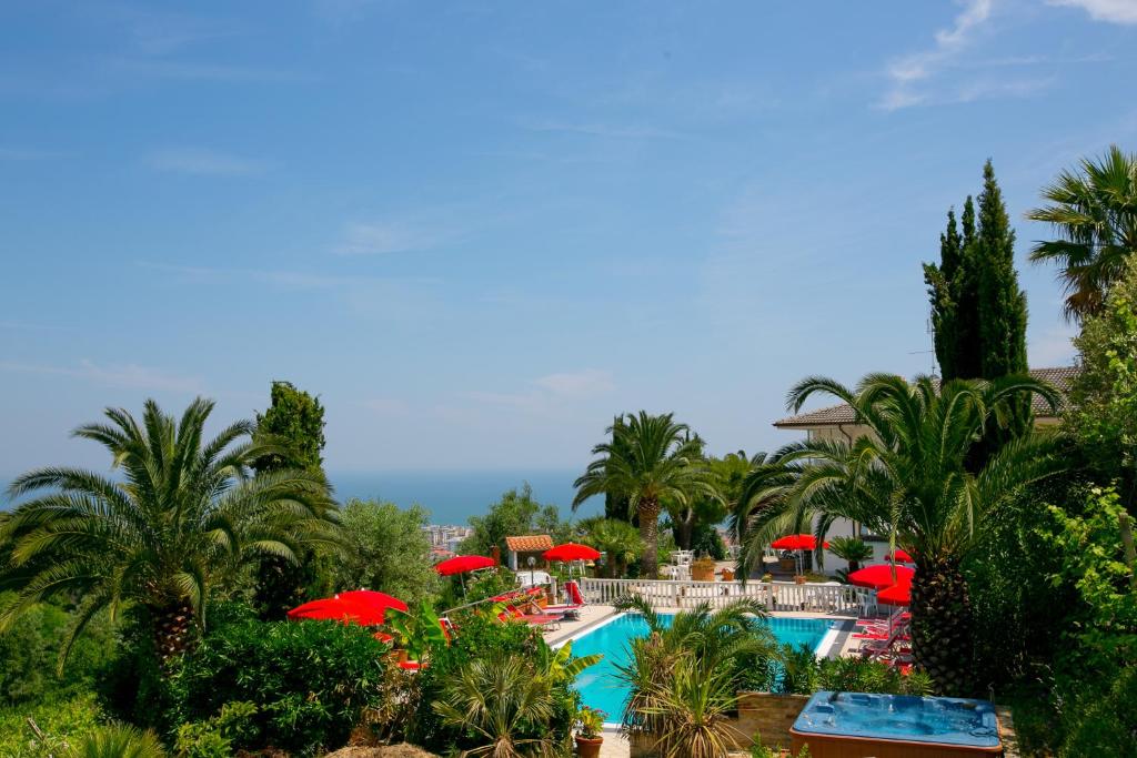 un resort con piscina con ombrelloni rossi di La Panoramica a San Benedetto del Tronto