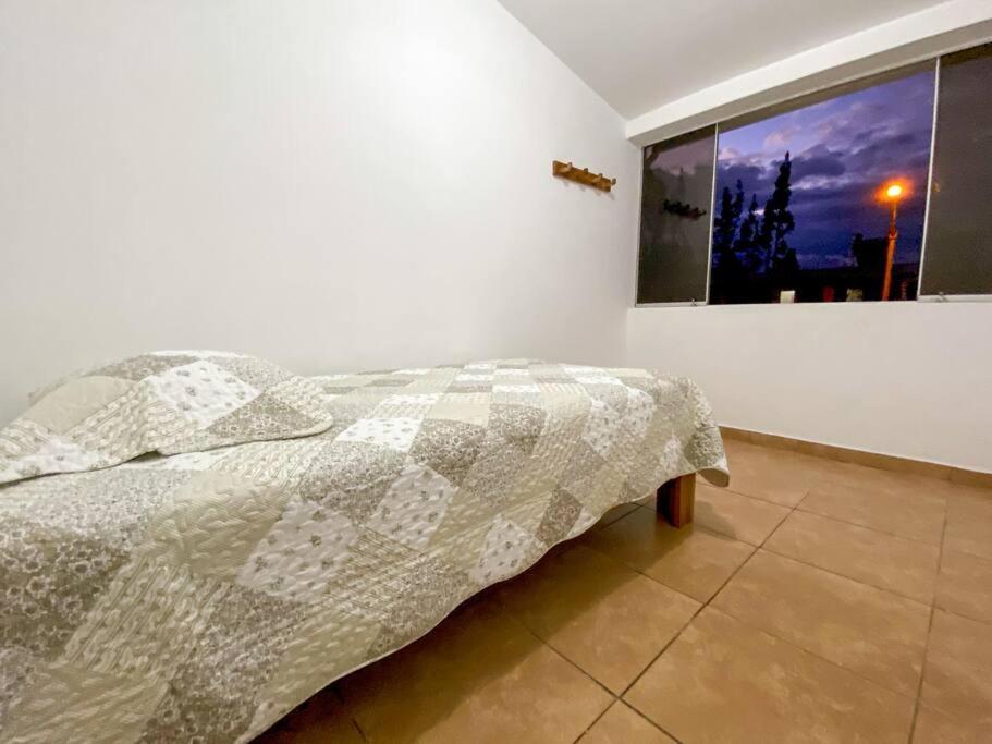 a bed in a white room with a window at Mountain Home in Huaraz