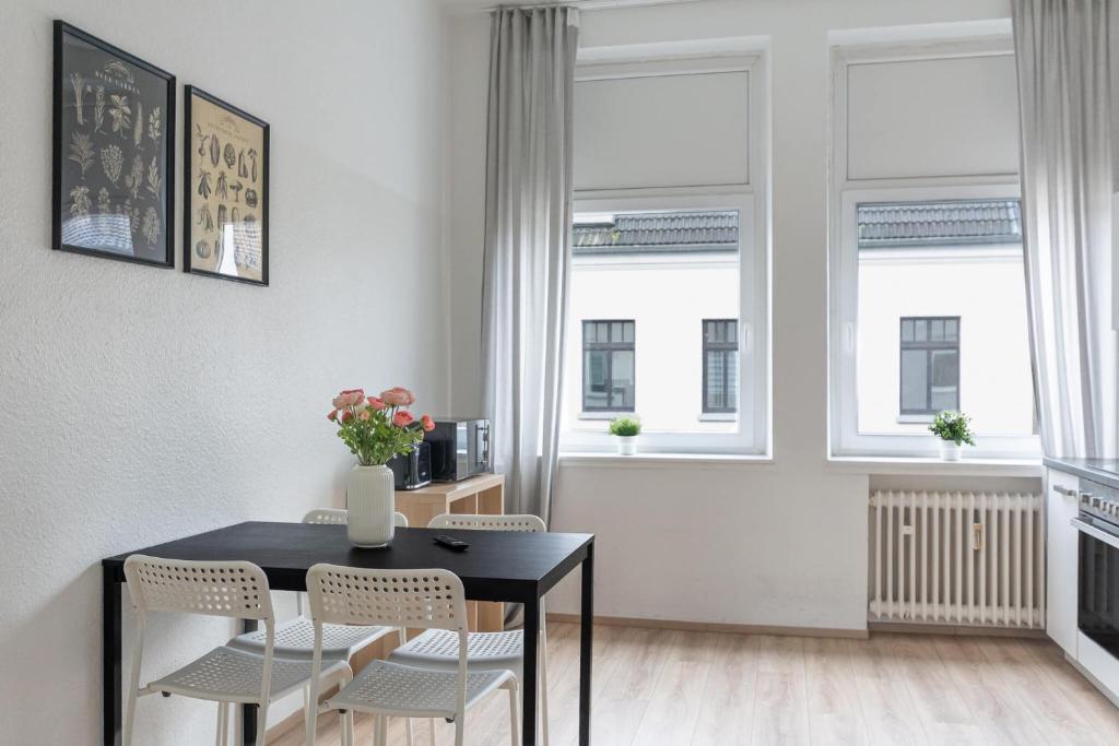 een eetkamer met een zwarte tafel en stoelen en ramen bij T&K Apartments - Apartments 20 Min to MESSE DUS in Krefeld