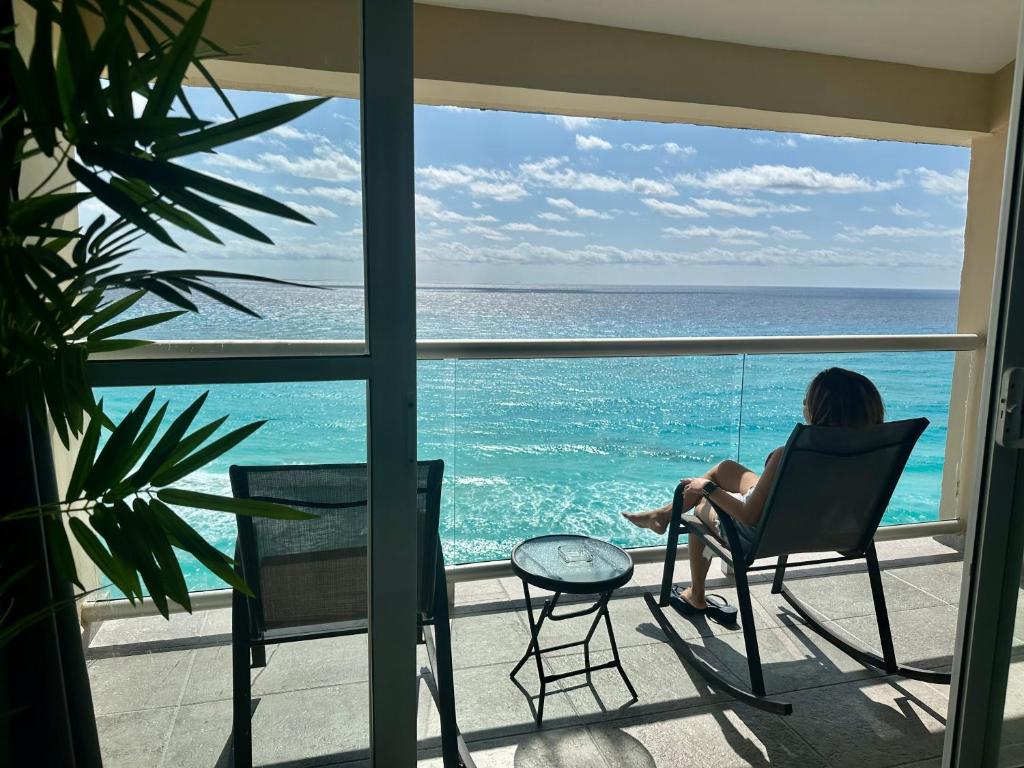 a woman sitting in a chair looking out at the ocean at Beachfront Penthouse (best location, 3 beds, 2 balconies) in Cancún