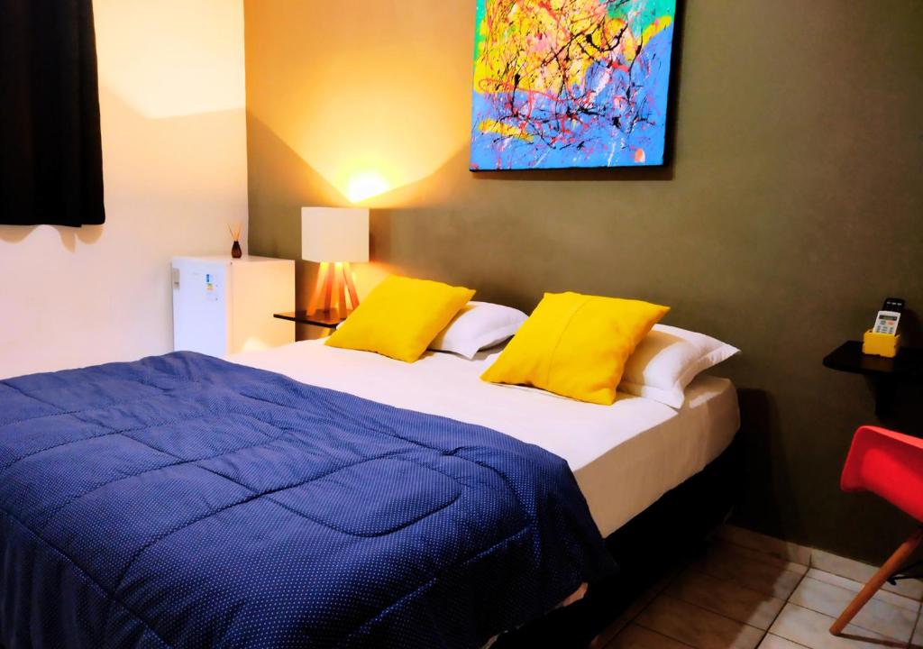 a bedroom with a bed with yellow pillows and a painting at Nomad - Norte Sul, Cambui in Campinas