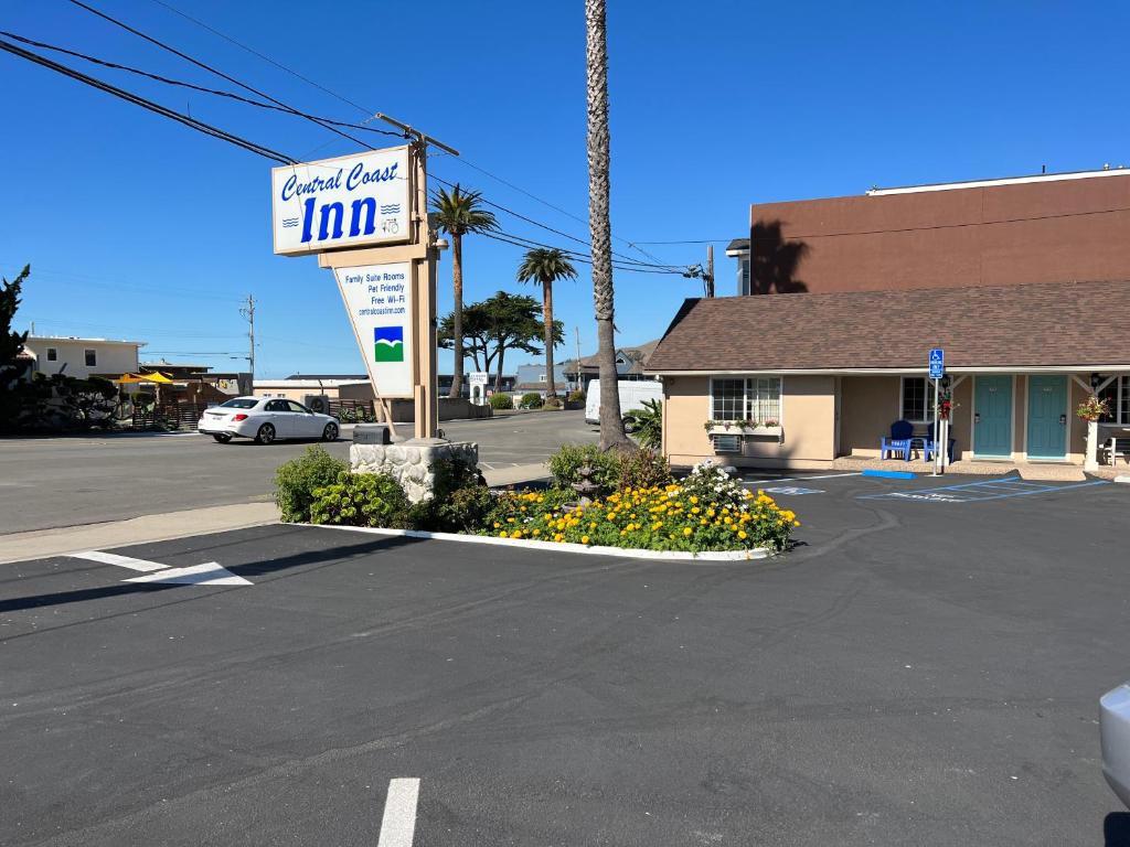 a parking lot with a hotel car inn sign and flowers at Central Coast Inn in Cayucos