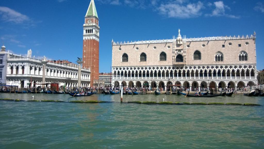 um edifício com uma torre de relógio ao lado de um rio em In Venice Back To San Marco tourist apartment em Veneza