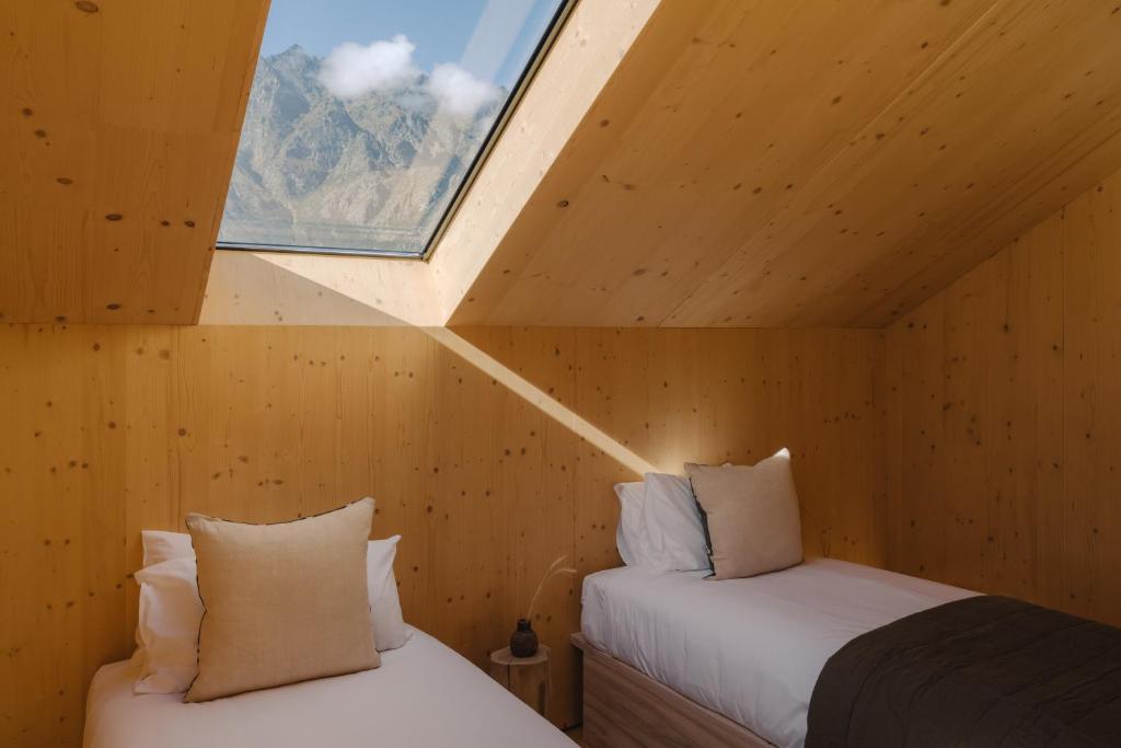 two beds in a wooden room with a window at The Earth House @ Jacks Point in Frankton