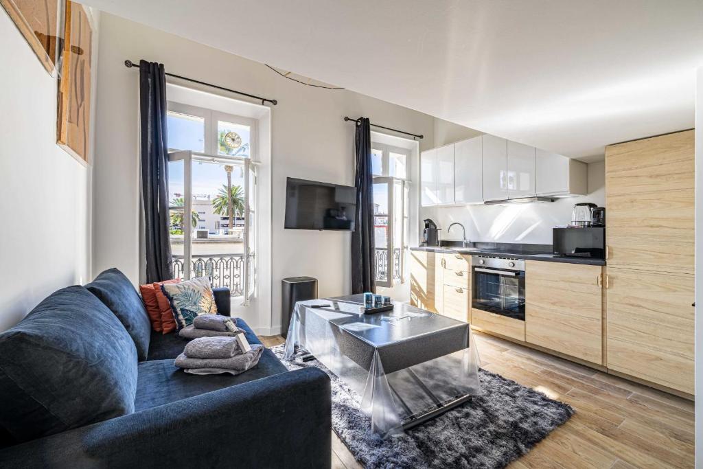 un salon avec un canapé bleu et une cuisine dans l'établissement Quiet apartment - parking and secure residence, à Cannes