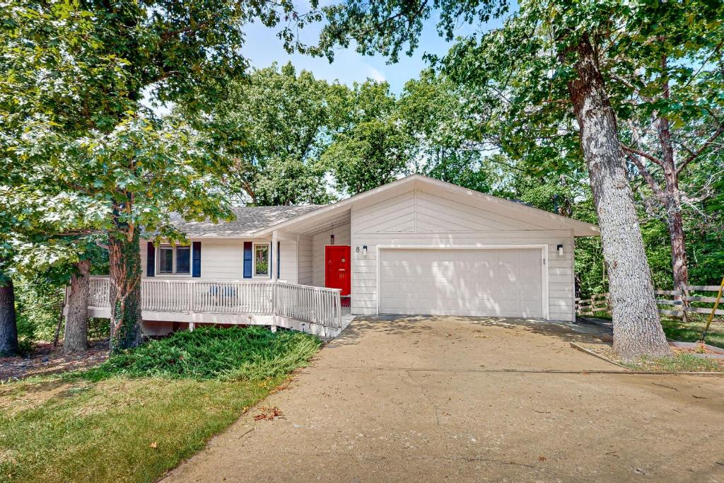 a white house with a red door and a garage at La Bella Vida at Bella Vista in Bella Vista
