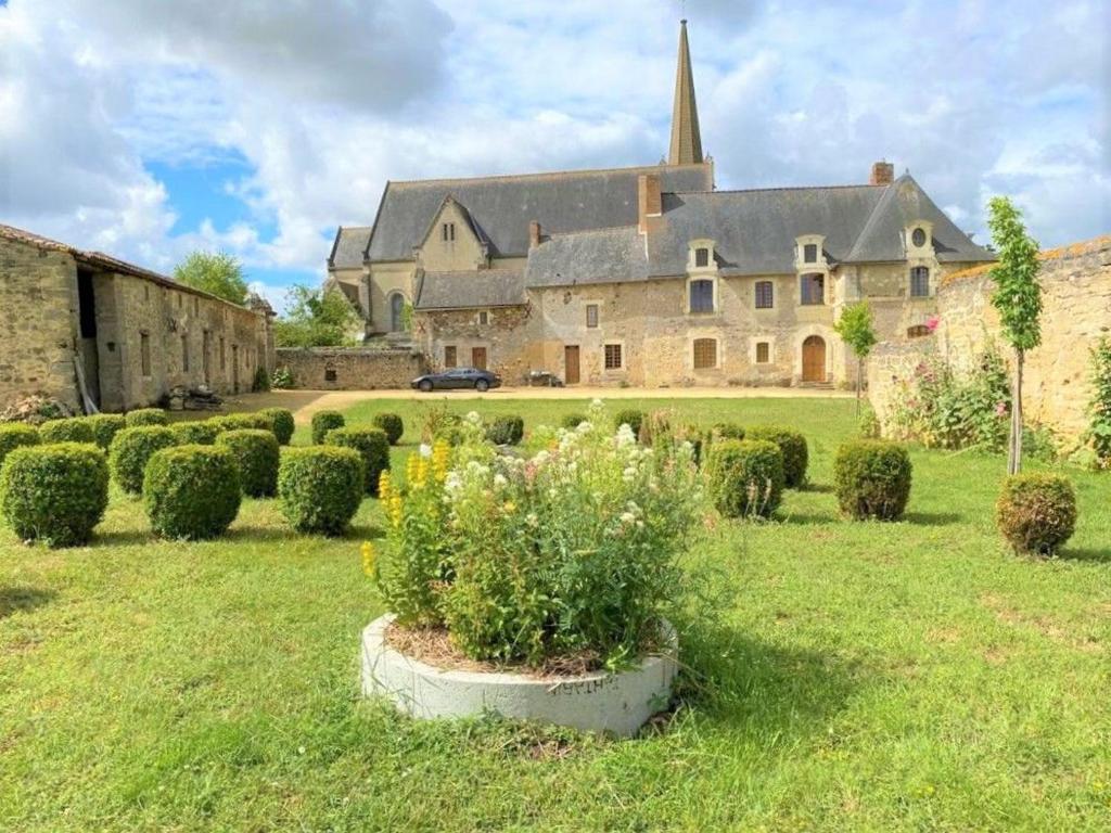 ein großes Haus mit Büschen im Hof in der Unterkunft Guestroom Doué-en-Anjou, 1 pièce, 2 personnes - FR-1-622-63 in Méa