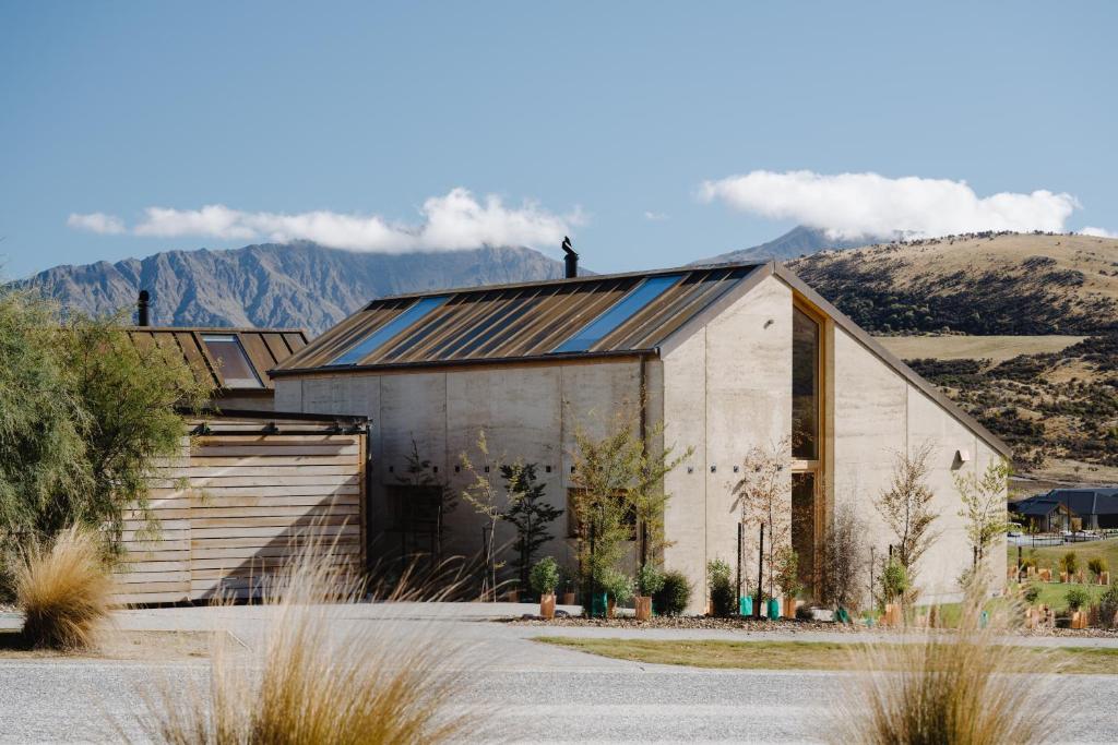 a large concrete building with mountains in the background at Jacks Point - Earth House in Frankton Wharf