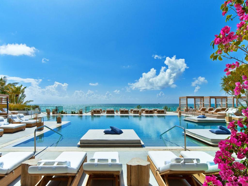 einen Pool mit Liegestühlen und das Meer im Hintergrund in der Unterkunft 1 Hotel South Beach in Miami Beach