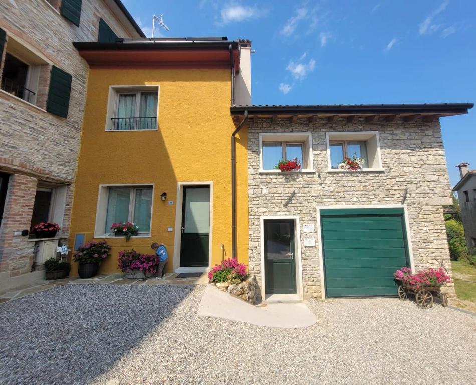 a yellow brick house with a green garage at Ca Marinella in Combai