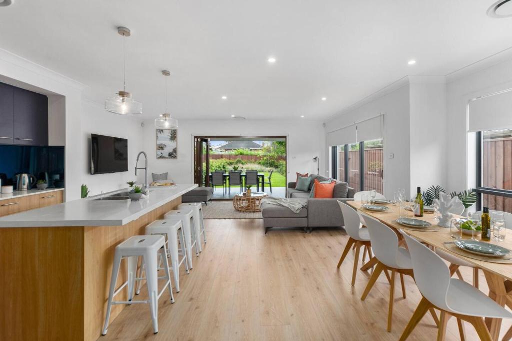 East Corrimal Escape - Beautiful Beachside Living في ولونغونغ: مطبخ وغرفة معيشة مع طاولة وكراسي