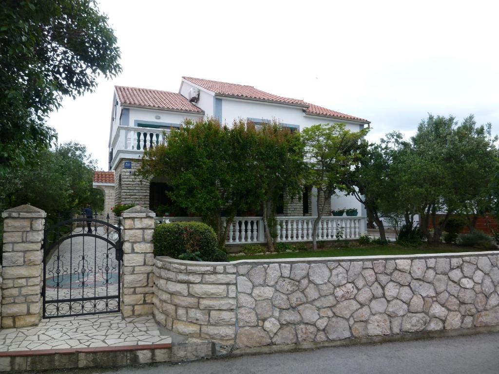 een wit huis met een hek en een stenen muur bij Apartments Bilava in Betina