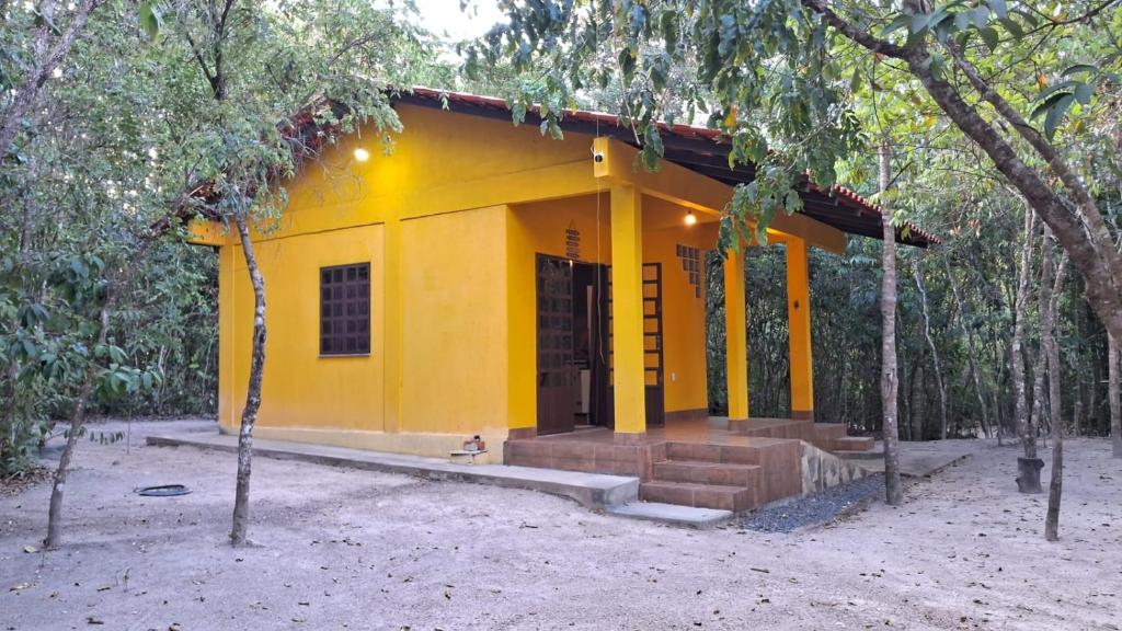 una casa amarilla en medio de un bosque en Recanto Gira Cerrado, en Cavalcante