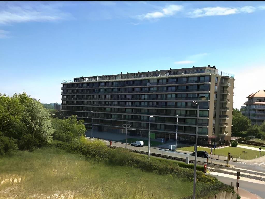 ein großes Gebäude mit Autobahn davor in der Unterkunft Corner apartment near the sea with terrace in Blankenberge