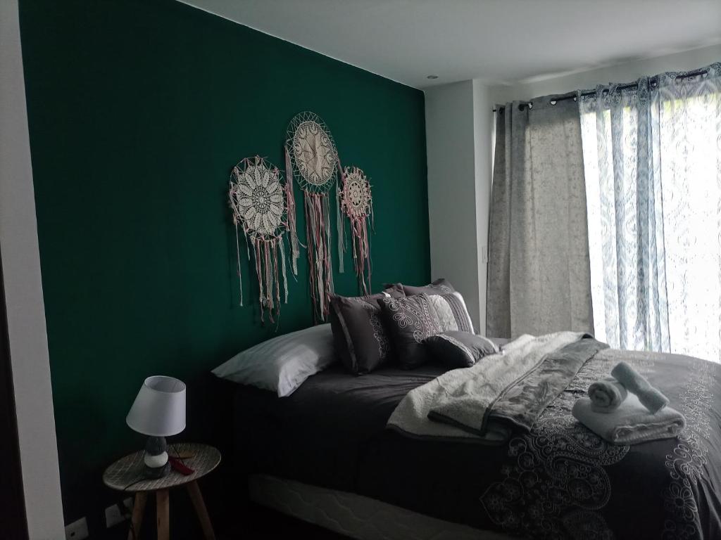 Un dormitorio con una pared de acento verde y una cama en Suite Zen, en Guatemala