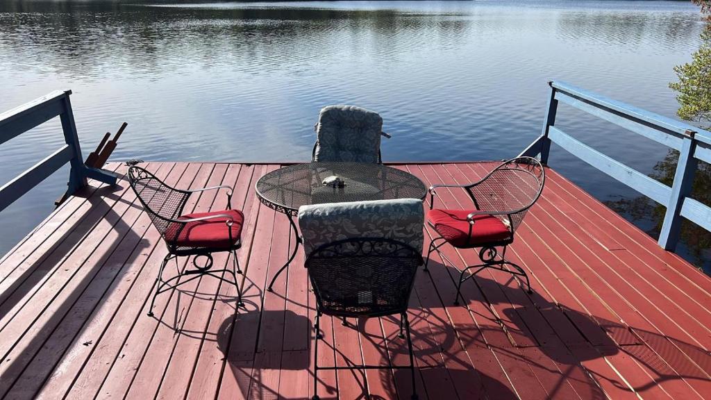 una mesa y sillas sentadas en un muelle cerca del agua en Stunning Lakefront Home - Swim, Fish, Kayak, HotTub, en Long Pond