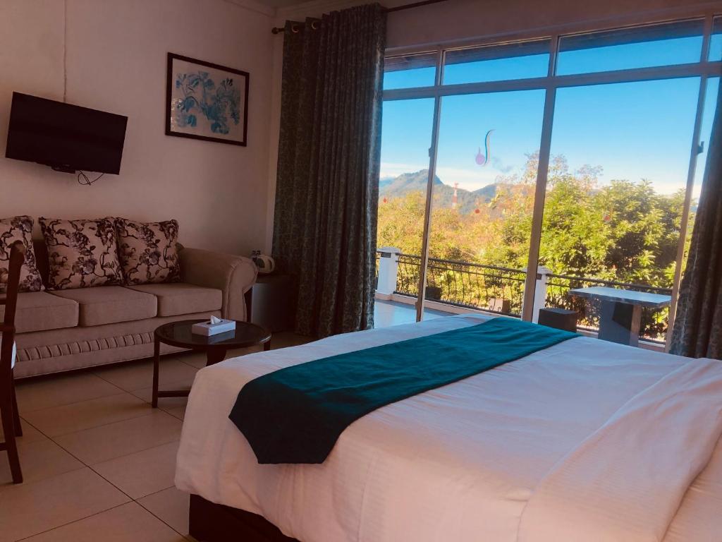 a bedroom with a bed and a couch and a large window at Elegant Hotel in Kandy