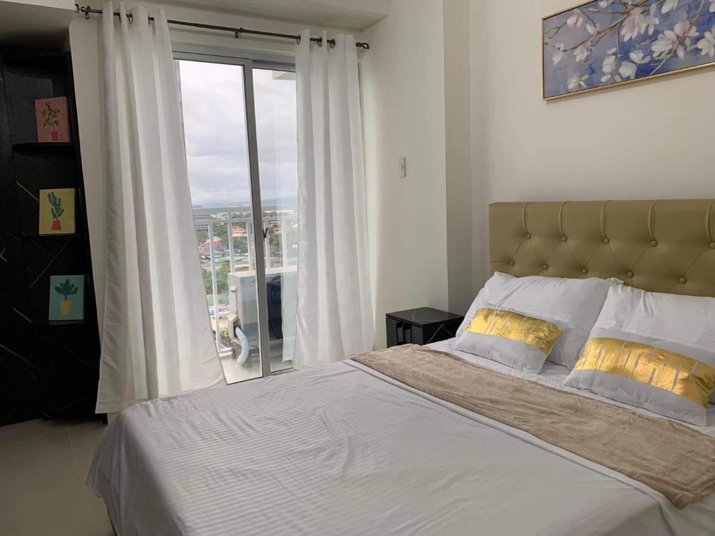 - une chambre avec un grand lit et une grande fenêtre dans l'établissement INSPIRIA CONDOMINIUM TOWER DAVAO, à Davao