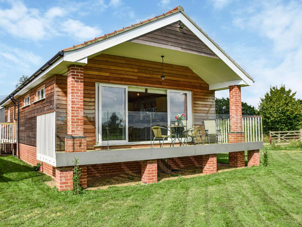 ein kleines Haus mit einer Terrasse mit einem Tisch in der Unterkunft Cedar Lodge in Old Buckenham