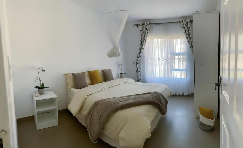 a white bedroom with a large bed and a window at Msasa Views Cottage in Juliasdale