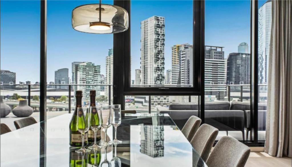 a dining room with a glass table with wine bottles at Luxury Penthouse with Astonishing Bay and City Views in Melbourne