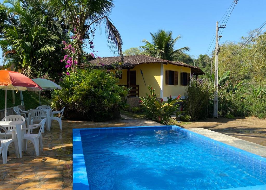 a villa with a swimming pool in front of a house at Pouso Familiar - Cantinho das Águas in Paraty