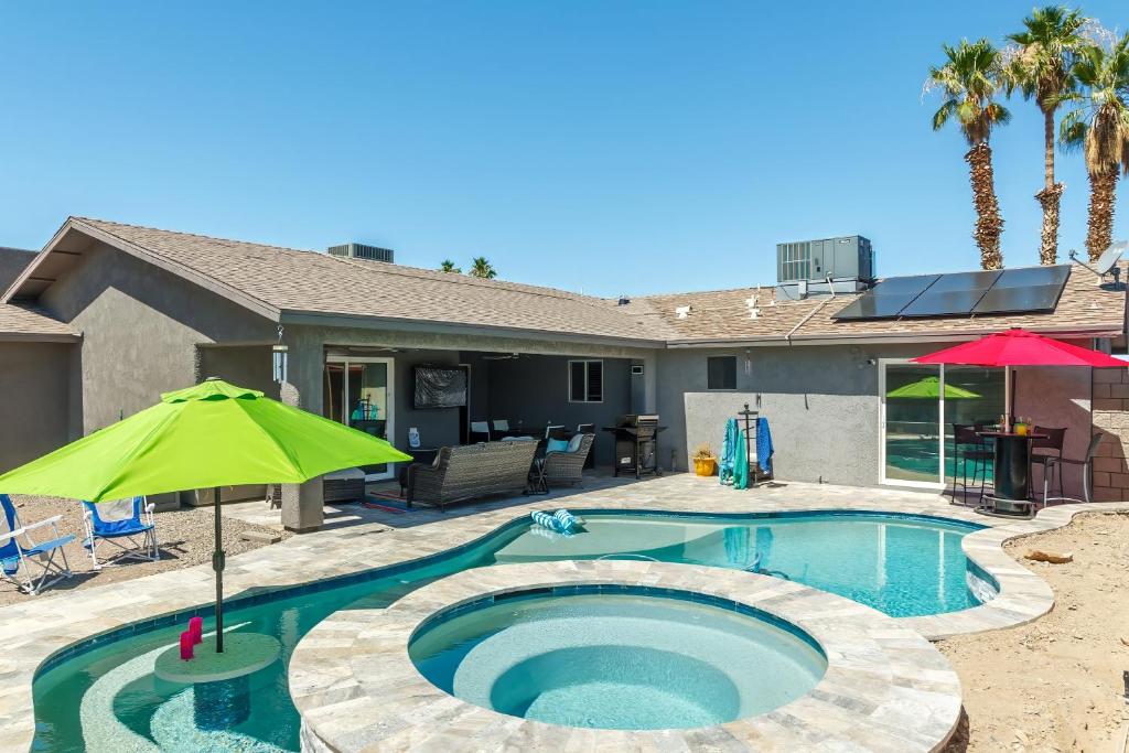 a swimming pool with an umbrella and a house at Coral Beauty! Heated Pool & Spa! in Lake Havasu City