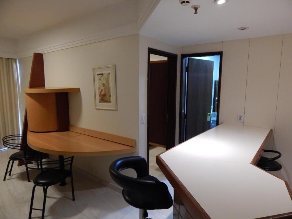 ブラジリアにあるJK Apart Hotel - Manhattanのデスク、椅子、テーブルが備わる客室です。