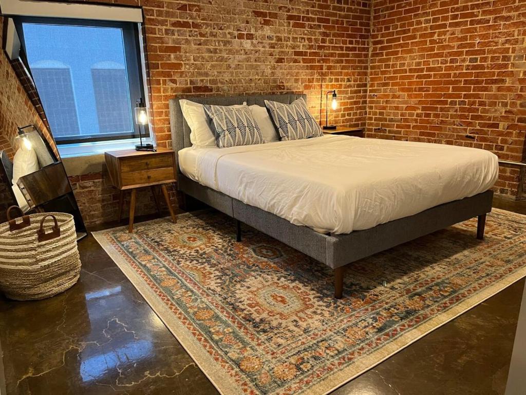 ein Schlafzimmer mit einem Bett und einer Ziegelwand in der Unterkunft Luxury 2 Bedroom Apt With Exposed Brick Downtown in Roanoke