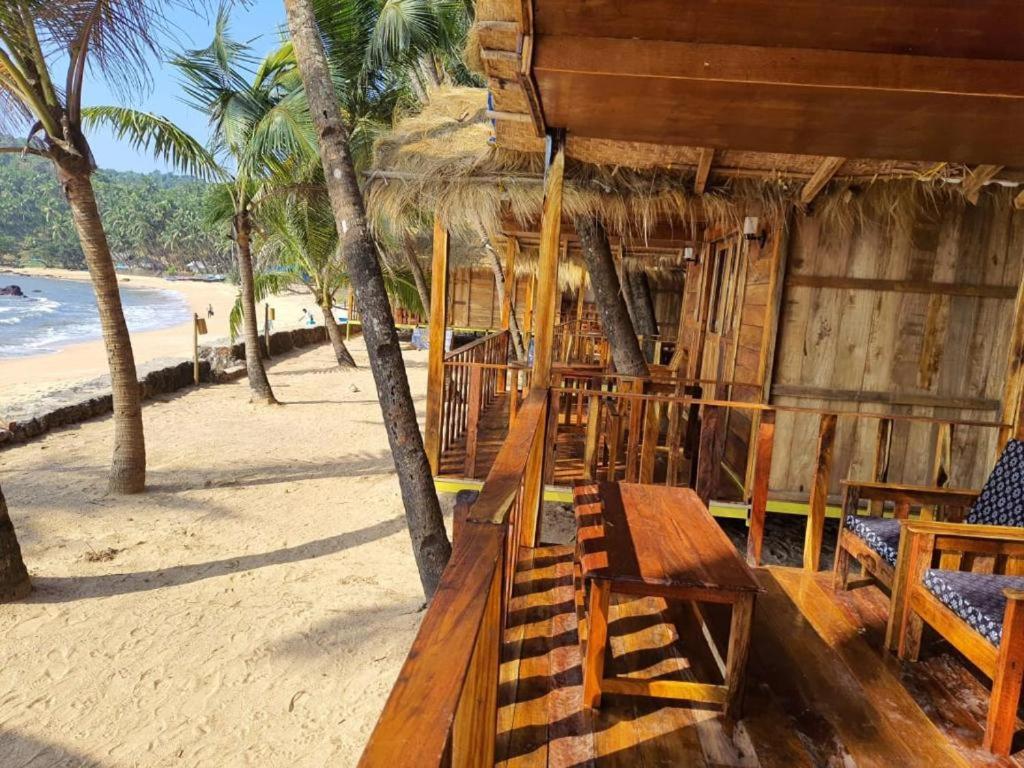 a wooden hut on the beach with palm trees at Sea Front Cottage Little Khola in Cola