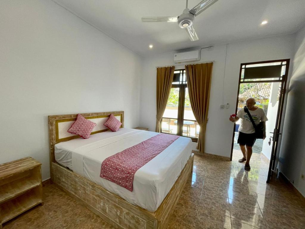 Una mujer entrando en un dormitorio con una cama grande en Asri BALI SANUR Premier Suites, en Sanur