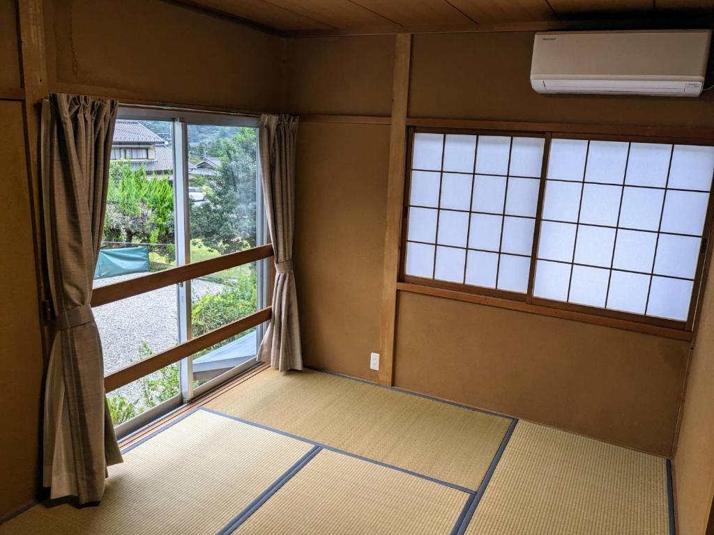 ein leeres Zimmer mit zwei großen Fenstern in einem Zimmer in der Unterkunft 下呂スプリングスロッジ in Gero