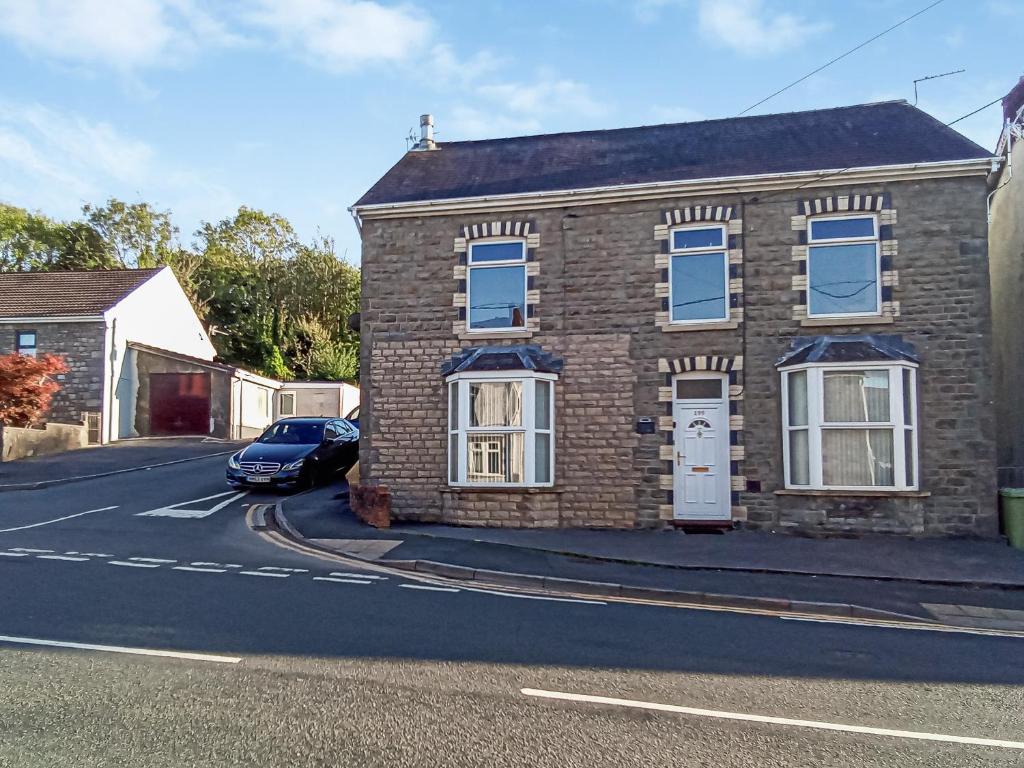 a brick house with a car parked in the street at Bradford House in Garnant