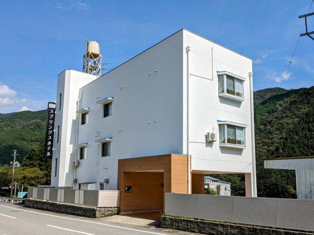 um edifício branco na berma de uma estrada em 下呂スプリングスホテル em Gero