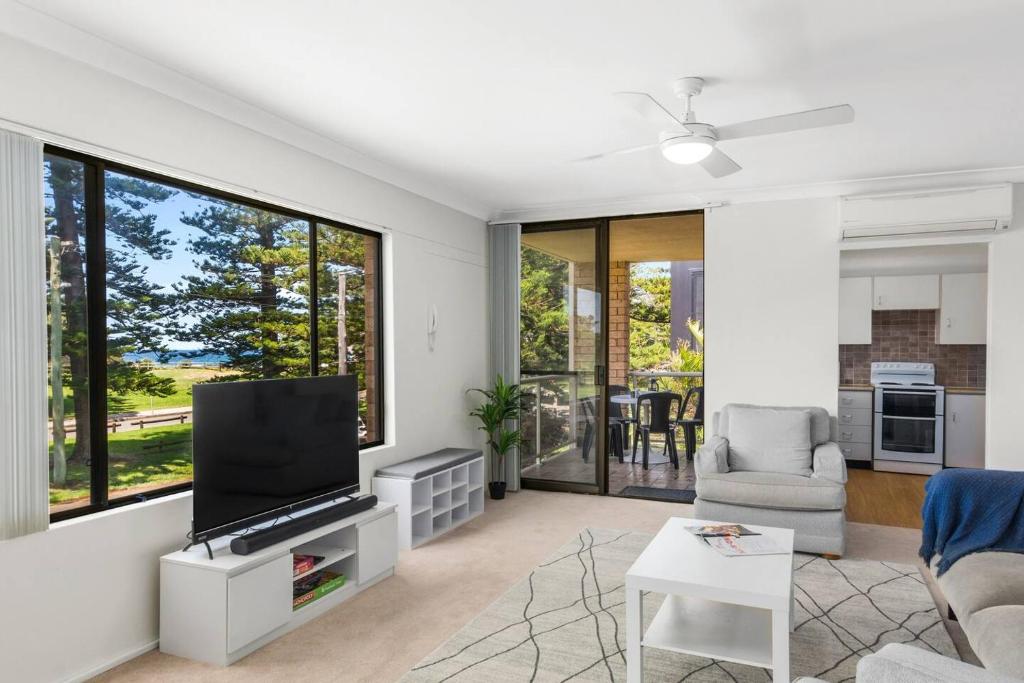 a living room with a flat screen tv and a couch at Esplanade Escape - Beachfront Family Bliss in Thirroul
