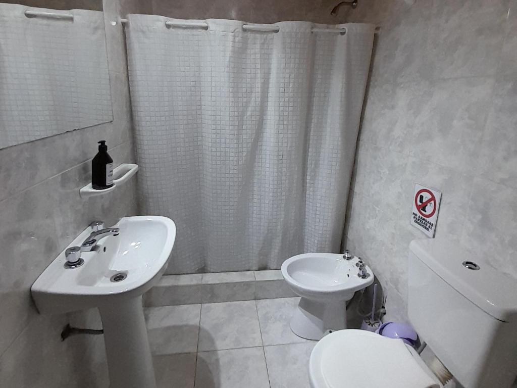 a white bathroom with a sink and a toilet at AYRES DEL SUR Patagonia in Río Gallegos