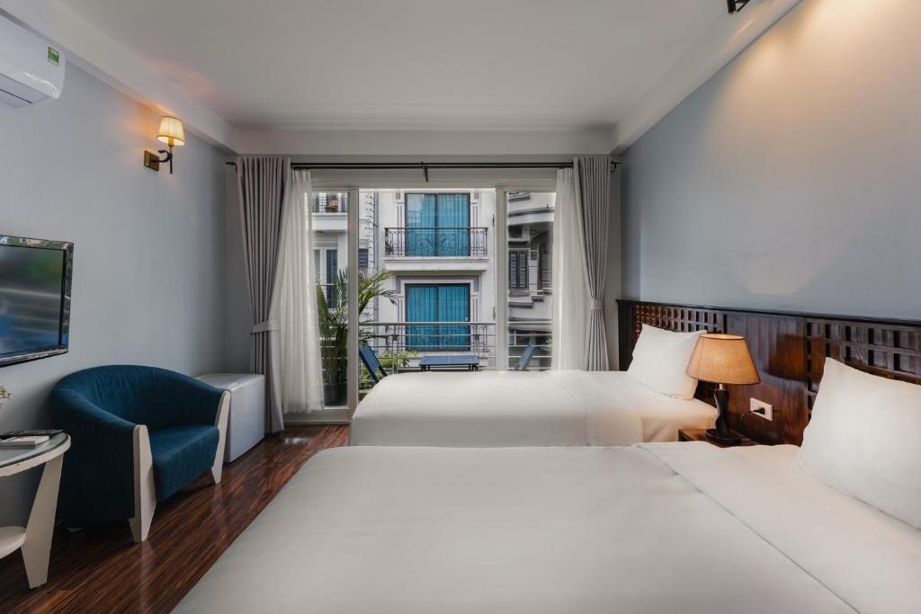 a hotel room with two beds and a window at Cheers Hostel Hanoi in Hanoi