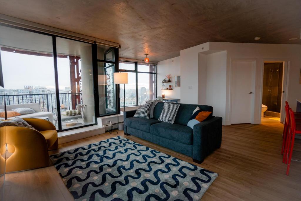 uma sala de estar com um sofá e janelas grandes em High rise Apartment em Vancouver