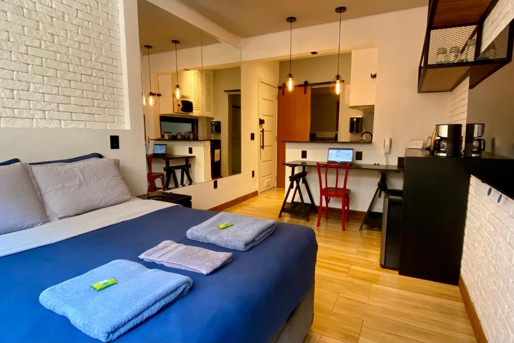 a bedroom with a blue bed and a kitchen at Loft lindo e aconchegante no centro de Teresópolis in Teresópolis