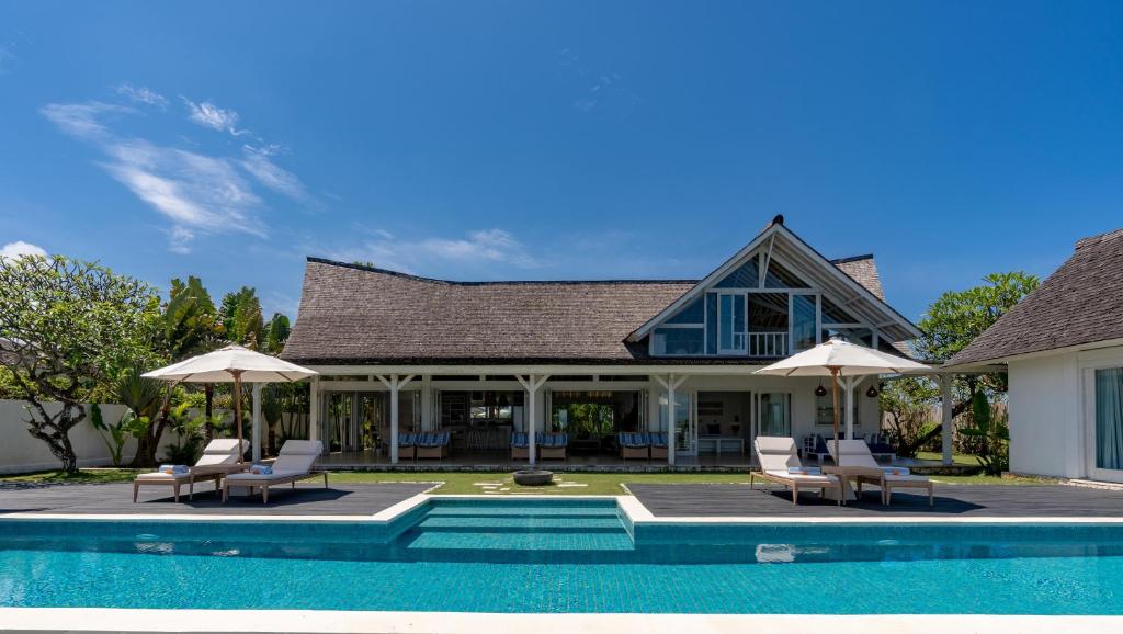 a house with a swimming pool with chairs and umbrellas at Casa del Mar in Nusa Lembongan