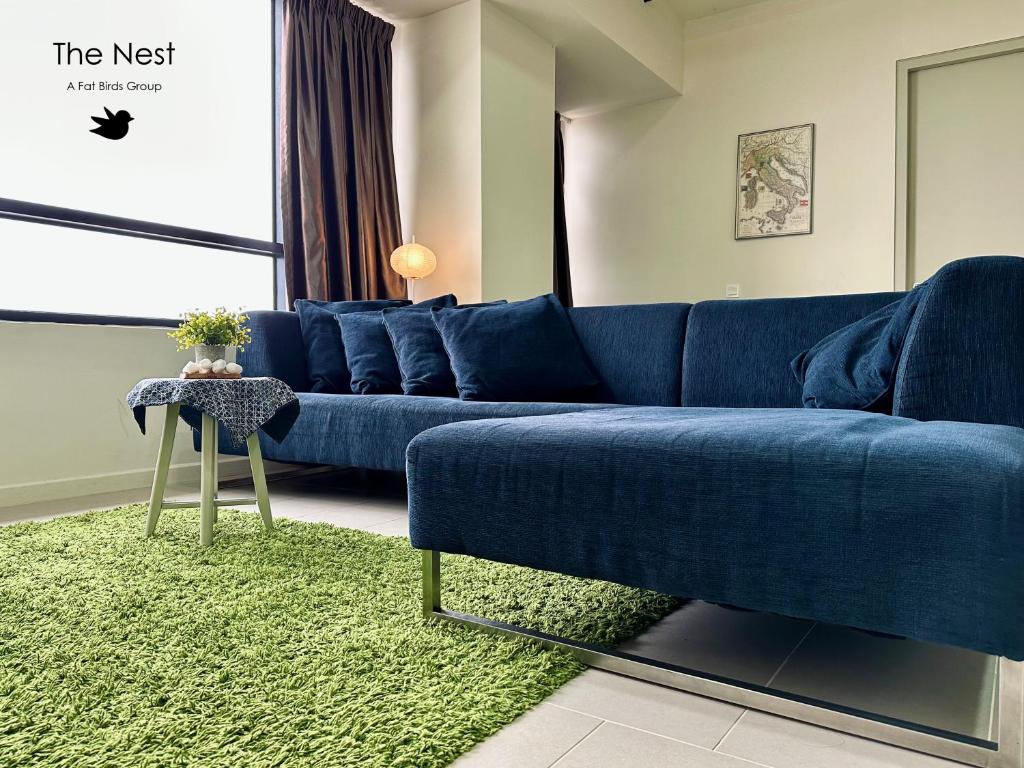 salon z niebieską kanapą i zielonym dywanem w obiekcie Cozy Tamarind Suites w mieście Cyberjaya