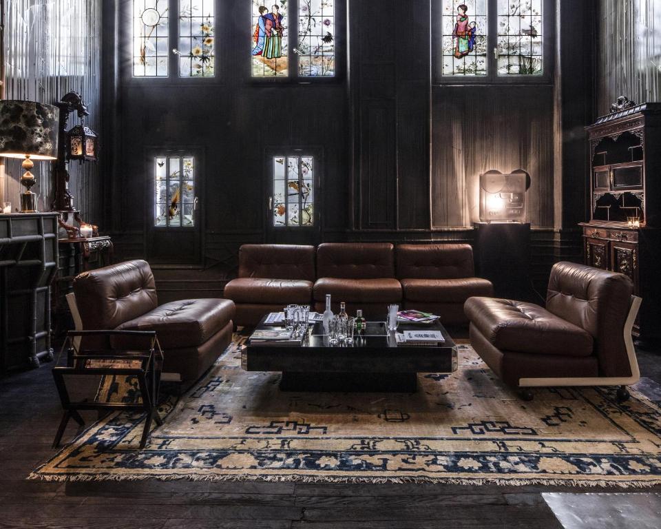 a living room with leather furniture and stained glass windows at Hotel Les Bains Paris in Paris