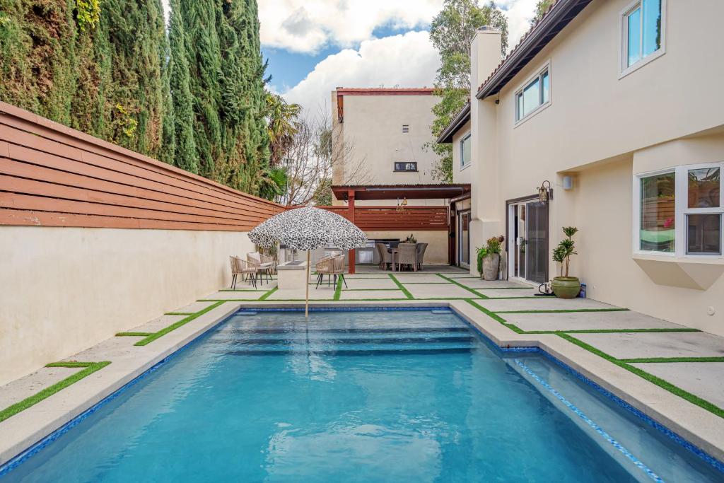 - une piscine avec un parasol à côté d'une maison dans l'établissement Beautiful 5 bedroom 8 bed sleeps up to 16 with pool near Universal Studios, à Los Angeles
