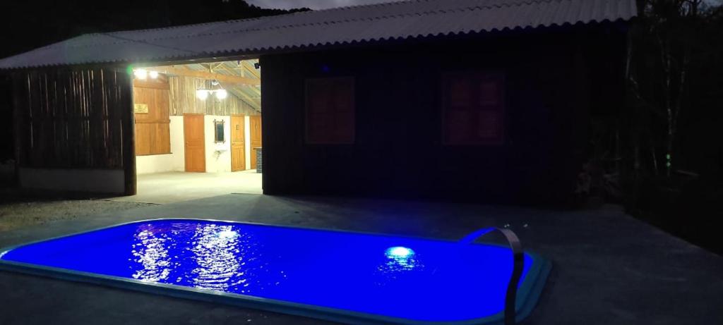 ein blauer Pool vor einem Haus in der Nacht in der Unterkunft Chácara Monte Cristo in Aguas Mornas