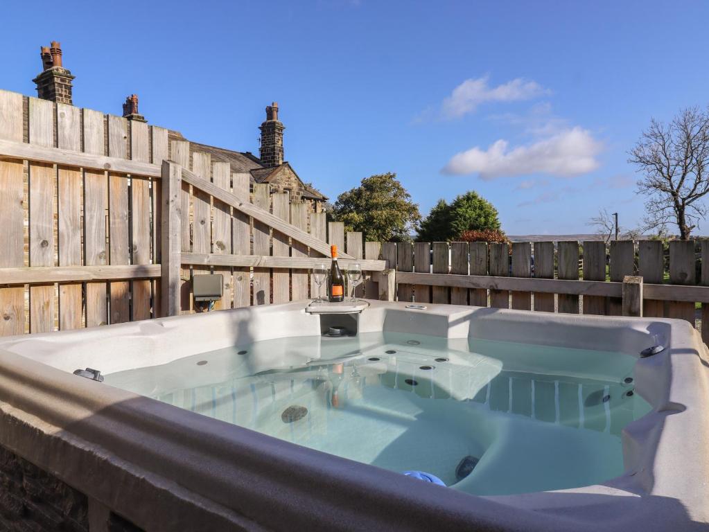 a hot tub on a fence with a bottle of wine at The Old Hen Shed in Ingrow