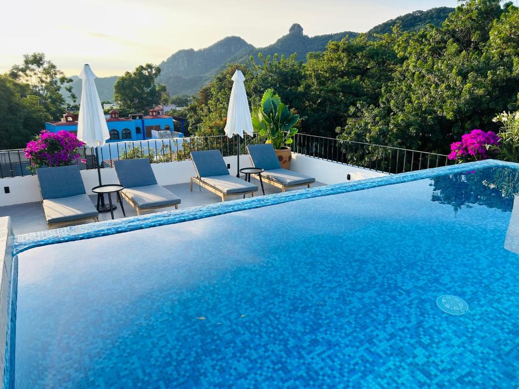 a swimming pool with chairs and umbrellas on a balcony at Tatala Hotel & Garden in Tepoztlán